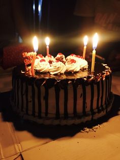 a chocolate cake with white frosting and lit candles