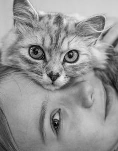 black and white photograph of a woman with a cat on her head, looking at the camera