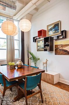 a dining room table with blue chairs and artwork on the wall