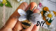 a hand holding a tiny gold and black flower on it's finger with the words diy written below