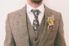 a man wearing a suit and tie with flowers on it's lapel flower