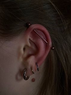 an ear with two piercings attached to it's side and one behind the ear