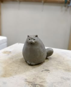 a clay cat sitting on top of a wooden table