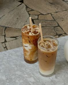 two iced drinks sitting on top of a table next to an egg shell shaped object