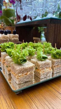 sandwiches with lettuce and olives are arranged on a tray in front of wine glasses