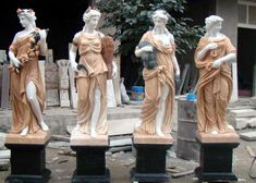 four statues of women holding flowers in front of a building