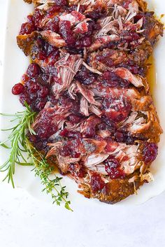 meat with cranberry sauce and herbs on a white platter, ready to be eaten