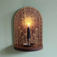 a candle that is on top of a wooden shelf with a light in the middle