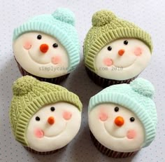 four cupcakes with frosting decorated like snowmen