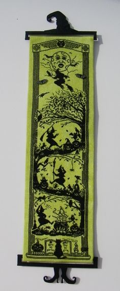 a green and black wall hanging with an image of trees in the sky on it