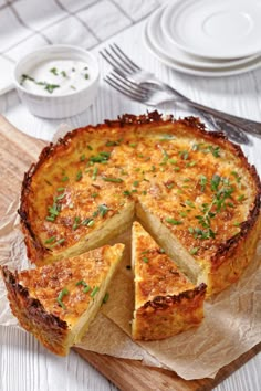 a quiche with one slice cut out on a cutting board