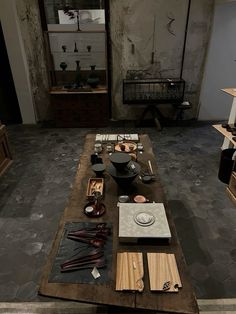 a table with plates and bowls on it in the middle of a room filled with other items