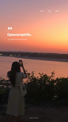 a woman taking a photo with her cell phone while the sun is setting in the background