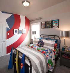 a bedroom with a captain america theme painted on the wall and pictures above the bed