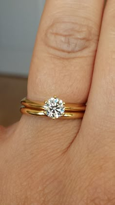 a woman's hand with two gold rings and a diamond