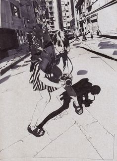 a black and white photo of a woman holding a camera on the sidewalk with buildings in the background