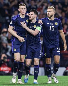 three soccer players are congratulating each other on the field