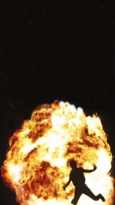 a person standing in front of a fireball with their arms out and legs spread wide