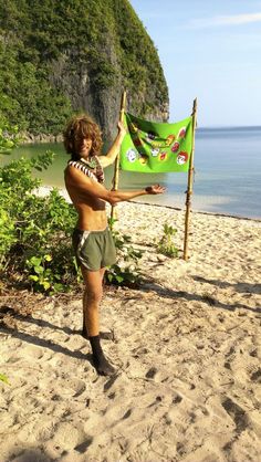 a man standing on top of a sandy beach holding a green flag