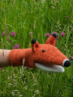 a knitted fox head is shown on the arm of a person in tall grass