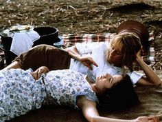 two young women laying on the ground next to each other with food in their hands