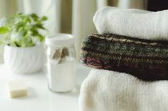 two towels stacked on top of each other next to a potted plant and glass jar