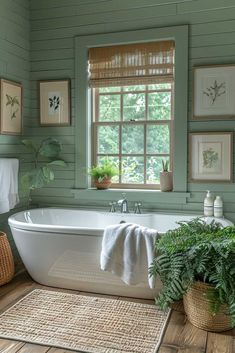 a white bath tub sitting next to a window in a room with wooden floors and green walls