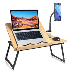 a laptop computer sitting on top of a wooden desk next to a mouse and cell phone