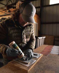 a man in a hat and gloves is working on some kind of woodworking project