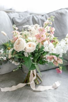 a bouquet of flowers sitting on top of a couch next to a white ribbon tied around it