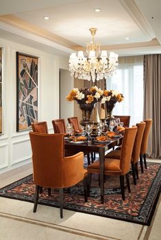 an elegant dining room with orange chairs and chandelier