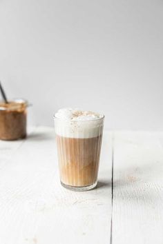 two cups filled with different kinds of food on top of a white wooden table next to each other