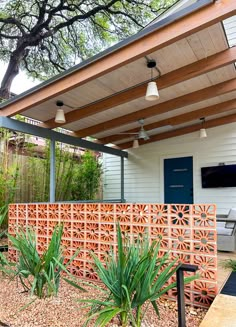 an outdoor living area with a wooden fence and plants on the side of the house