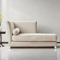 a white couch sitting next to a table with a vase on it's side