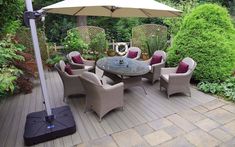 an outdoor dining area with patio furniture, umbrella and potted plants on the deck