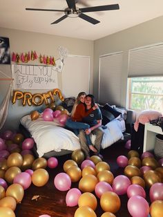 two women sitting on a bed surrounded by balloons