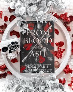 a plate with a skull and roses on it next to a book titled prom blood and ash