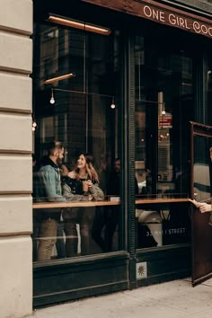 a man and woman standing in front of a restaurant window