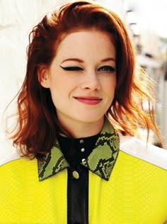 a woman with red hair wearing a yellow shirt and black tie