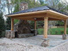 a stone patio with a fireplace and seating area in the middle, surrounded by brick pavers