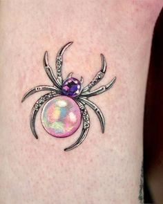 a spider tattoo on the side of a woman's leg with an orb in it