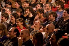 a group of people sitting next to each other in front of a man with his mouth open