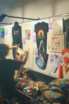 a person standing in front of a display of children's t - shirts and other items