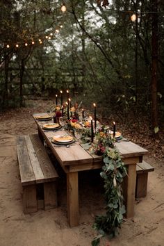 a wooden table topped with plates and candles