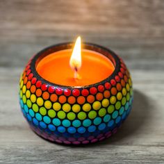 a brightly colored candle is lit on a wooden table with wood planks in the background