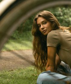 a woman sitting on the ground in front of a bicycle tire with her head down