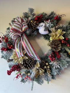 a christmas wreath with pine cones, holly berries and a white teddy bear on it