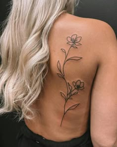 the back of a woman's shoulder with a flower tattoo on her left side