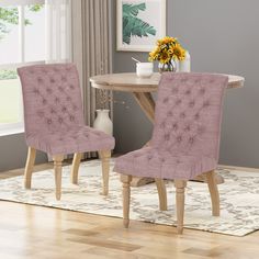 two pink chairs sitting next to each other on top of a wooden dining room table