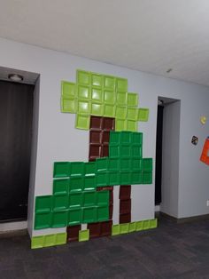 a room with a wall made out of lego blocks and a large green tree on the wall